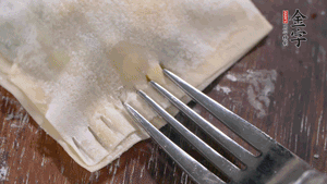 将馅料放在饺子皮上，边缘蘸水，另一片覆盖，用叉子边缘压紧定型。