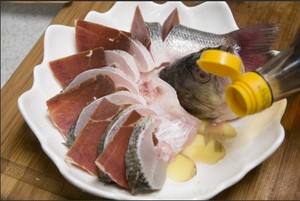 将处理好的鲈鱼放在盘中，撒上适量黄酒，姜片，腌制10分钟。