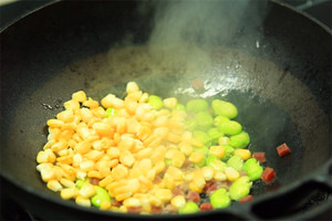 热油起锅后，加火腿丁煸香，然后加入玉米粒、蚕豆煸炒均匀，盛出备用。