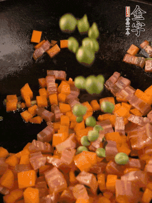 热油下锅，咸肉煸出香味后，加葱花、胡萝卜丁、豌豆翻炒。